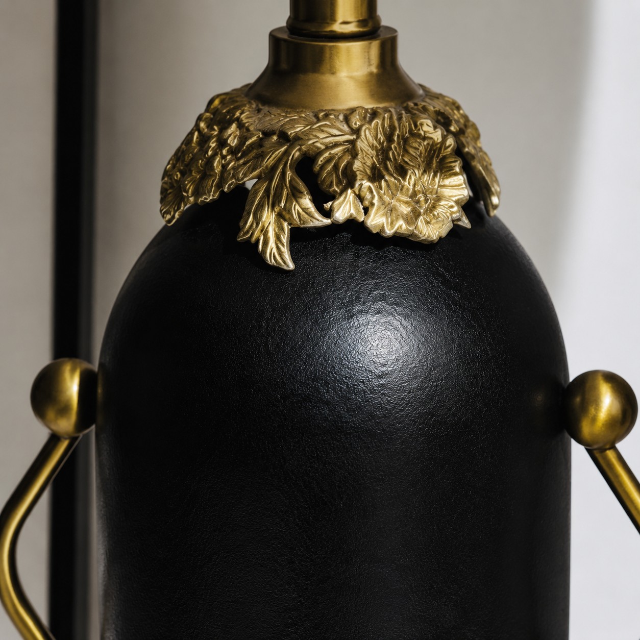 Close-up of matte black lamp body with antique brass-toned floral detail