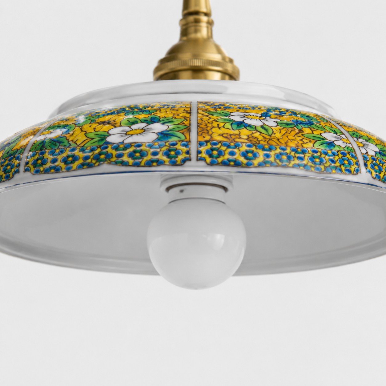 Close detail of yellow floral ceramic shade pattern and visible bulb opening